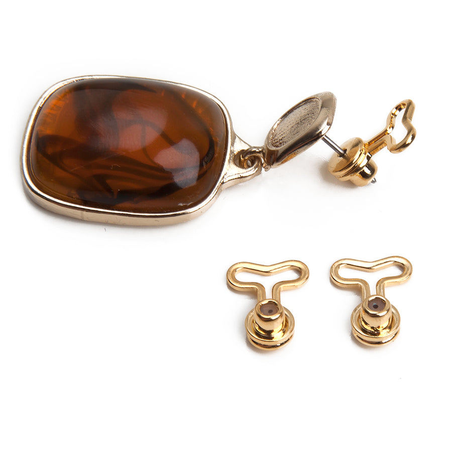 One pair of goldtone T-back T-shaped earring backs next to a brown stone bezeled earring showing how the earring back fits onto a post earring.