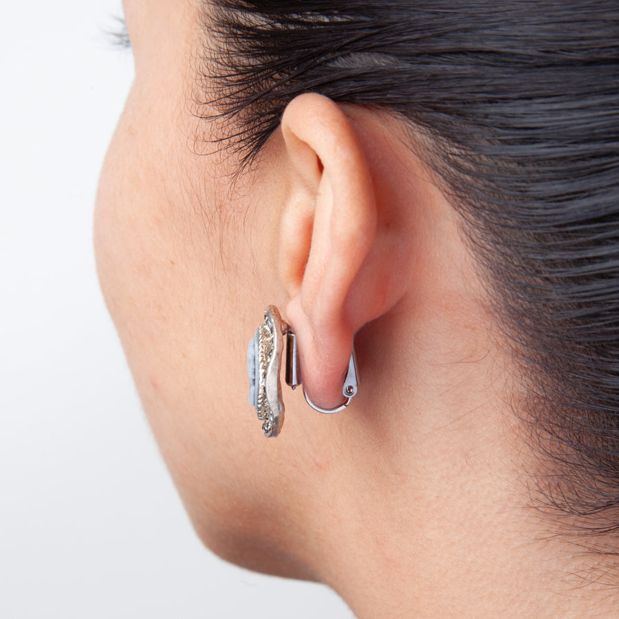 side view of woman's ear with post to clip on earring converters showing a large statement earrings converted to clip on earrings on a white background