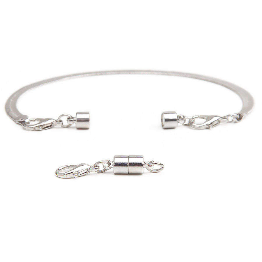One silver small barrel magnetic clasp in front of a silver bracelet with attached silver small barrel magnetic necklace clasp.