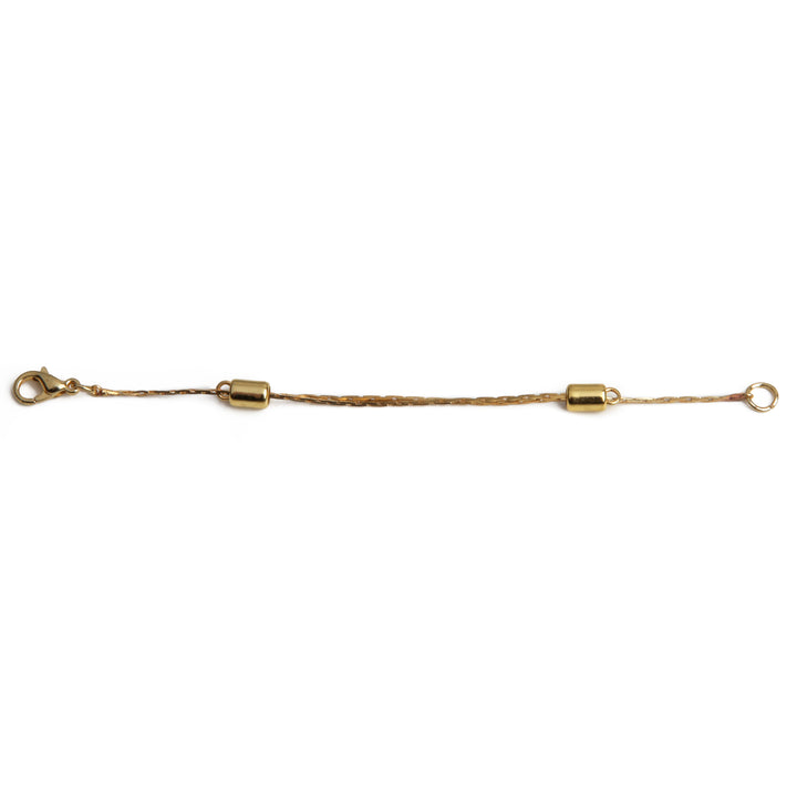 One gold adjustable necklace extender laid out on a white background.