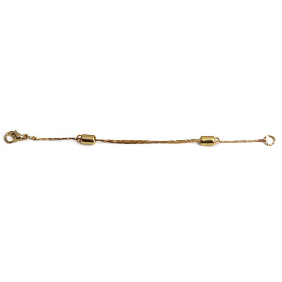 One gold adjustable necklace extender laid out on a white background.