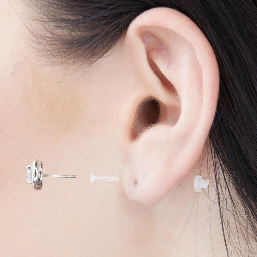 side view of an ear with a floating diamond earring, clear earring sleeve, and clear earring back to show how the sleeves are used when worn.