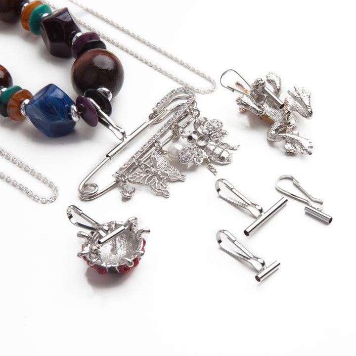 a small horizontal pin to pendant converter, a large horizontal pin converter, and a small vertical pin converter laid out below two silver necklaces and a large beaded necklace using pin converters with brooches.