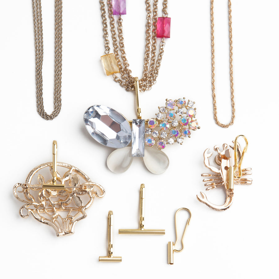 a small horizontal pin to pendant converter, a large horizontal pin converter, and a small vertical pin converter laid out below three gold necklaces using pin converters with brooches.