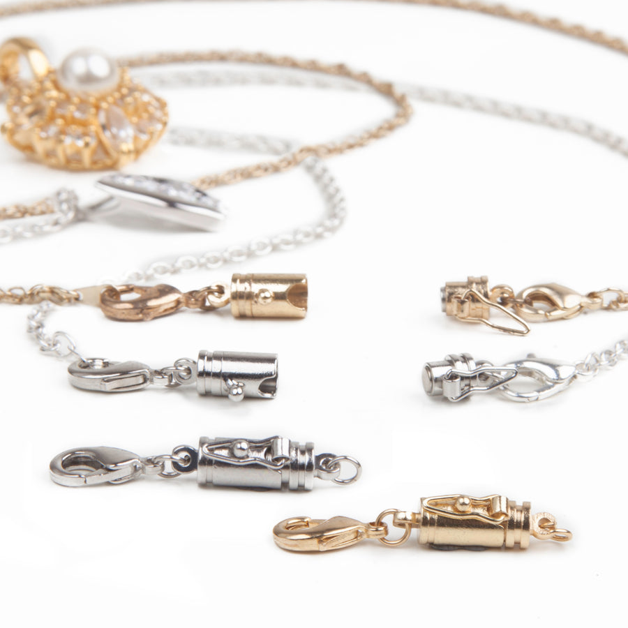 Two necklaces, one gold and one silver, laid out with attached magnetic jewelry clasps with a safety catch with two small magnetic clasps with safety catches in front.