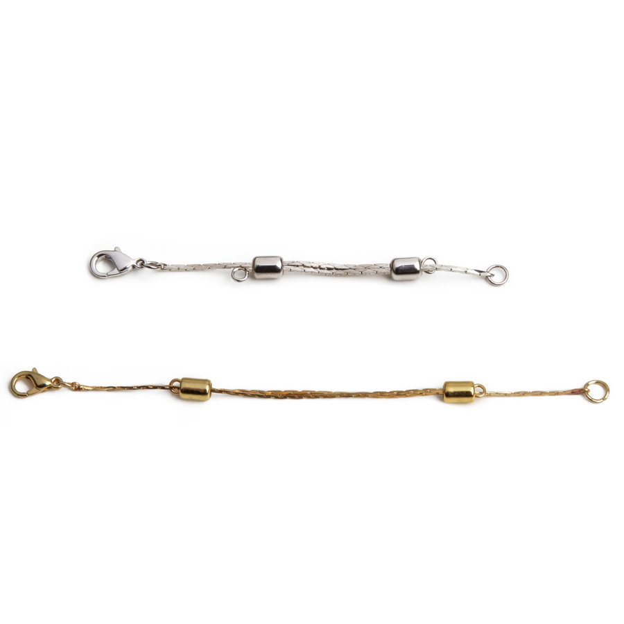 One small silver adjustable necklace extender laid out next to one large gold adjustable necklace extender.