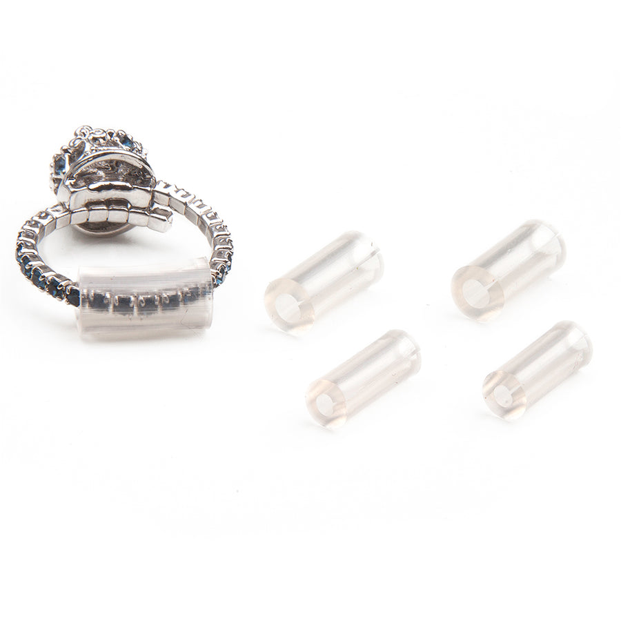four clear plastic tubes that are ring size adjusters laid out next to a silver diamond ring with one of the sizers in use.