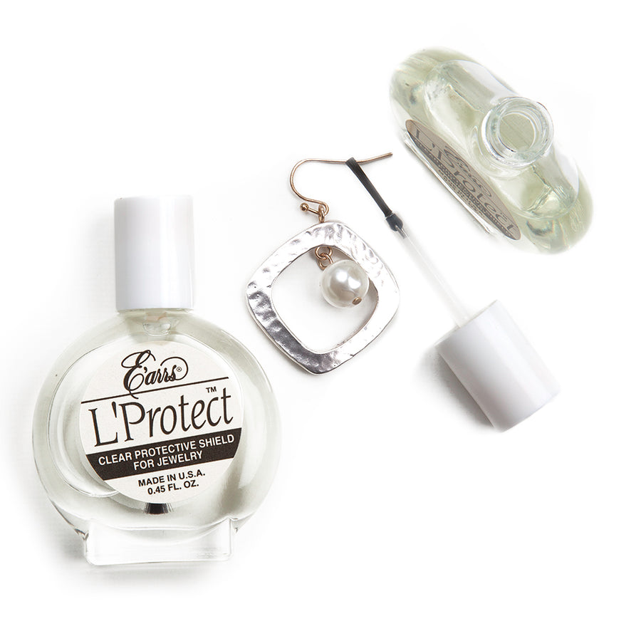 One bottle laid on its back with a label saying E'arrs L'Protect Clear Protective Shield for Jewelry, next to an open bottle with brush top cap being used on an earring.