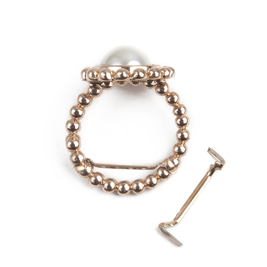 one gold women's ring size adjuster and guard next to a gold pearl ring with the sizer in use.