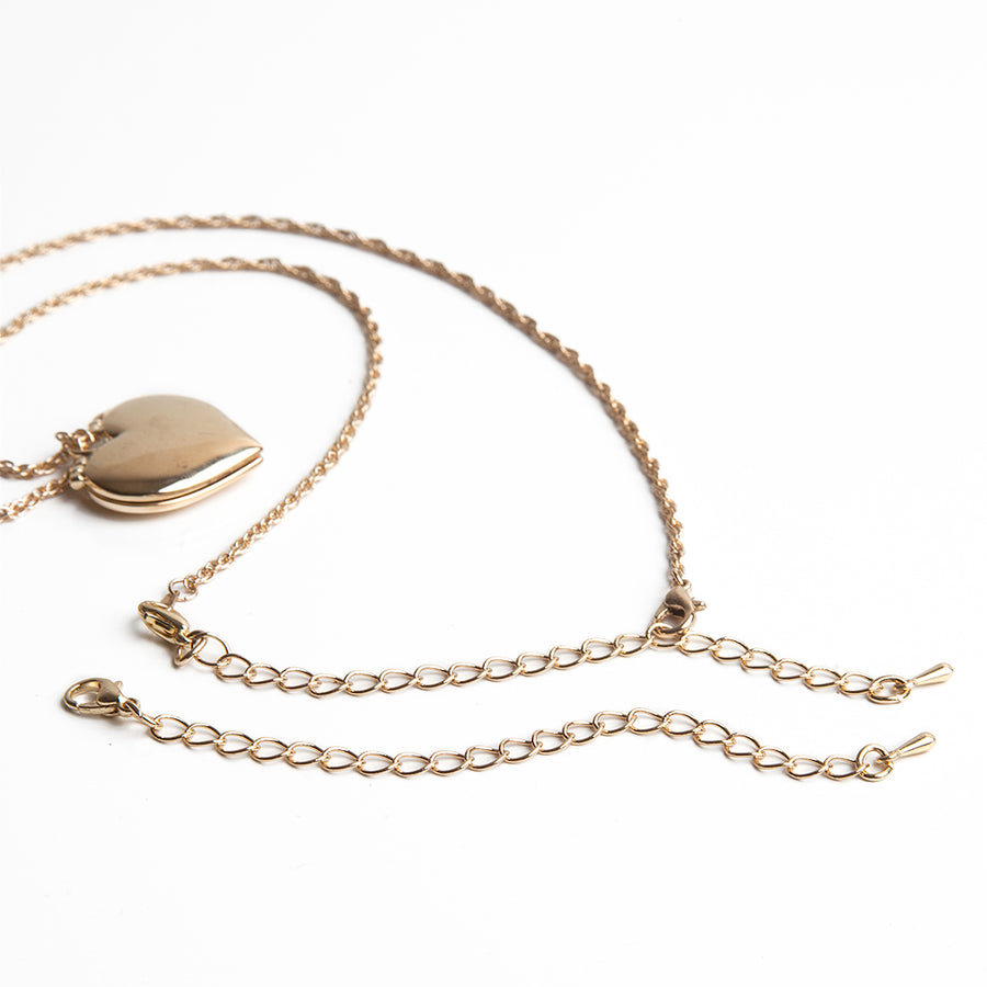 One gold necklace extender laid in front of a gold heart necklace with attached gold necklace extender.