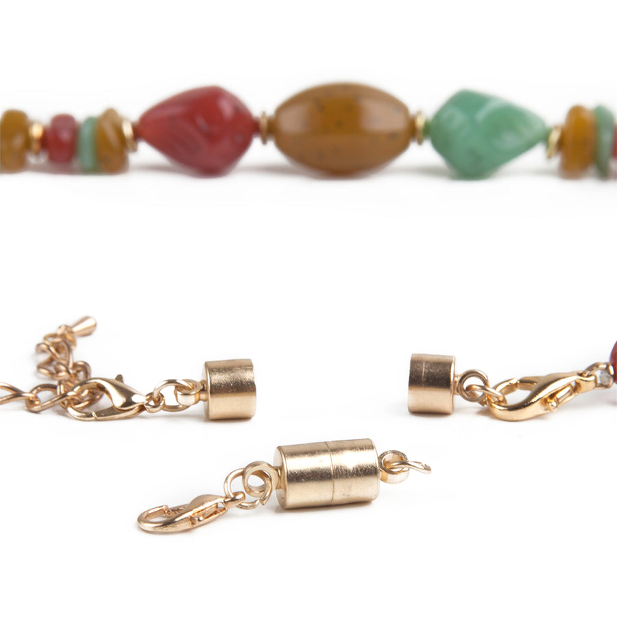 Large Barrel goldtone magnetic jewelry clasp in front of a large beaded necklace with an attached magnetic jewelry clasp.