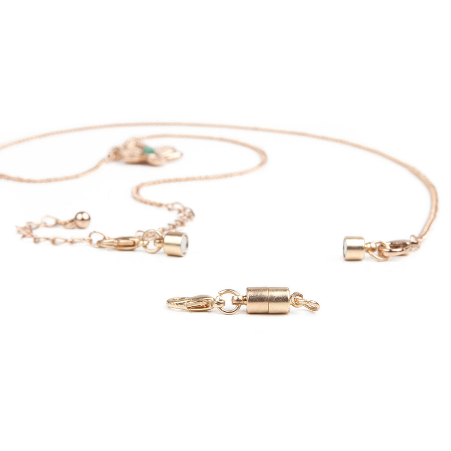 one small gold barrel magnetic clasp in front of a gold necklace with attached small gold barrel magnetic clasp.