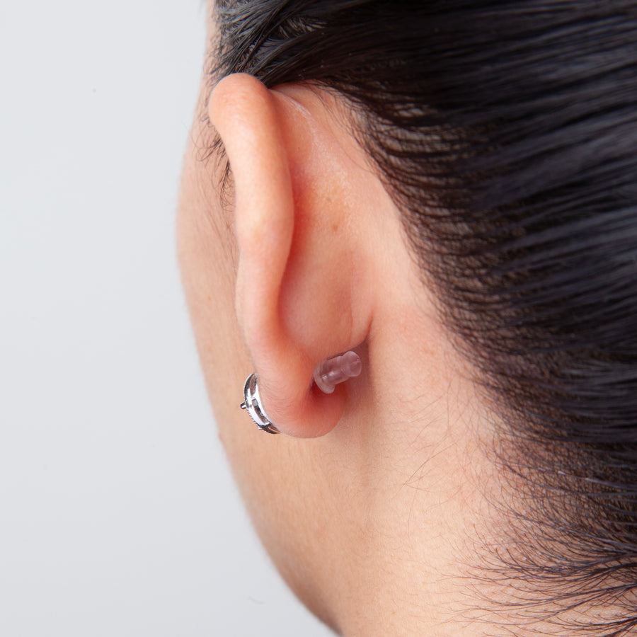 back view of an ear showing how a small, clear bullet-shaped earring back is worn with stud earrings.
