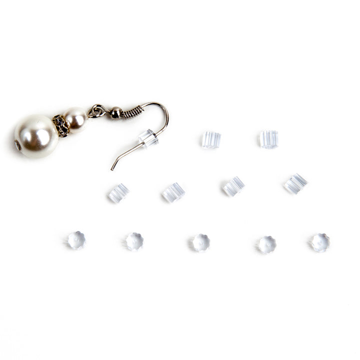 twelve small, clear earring backs laid out next to a wire dangle earring with one of the earring backs attached to show how it is used.