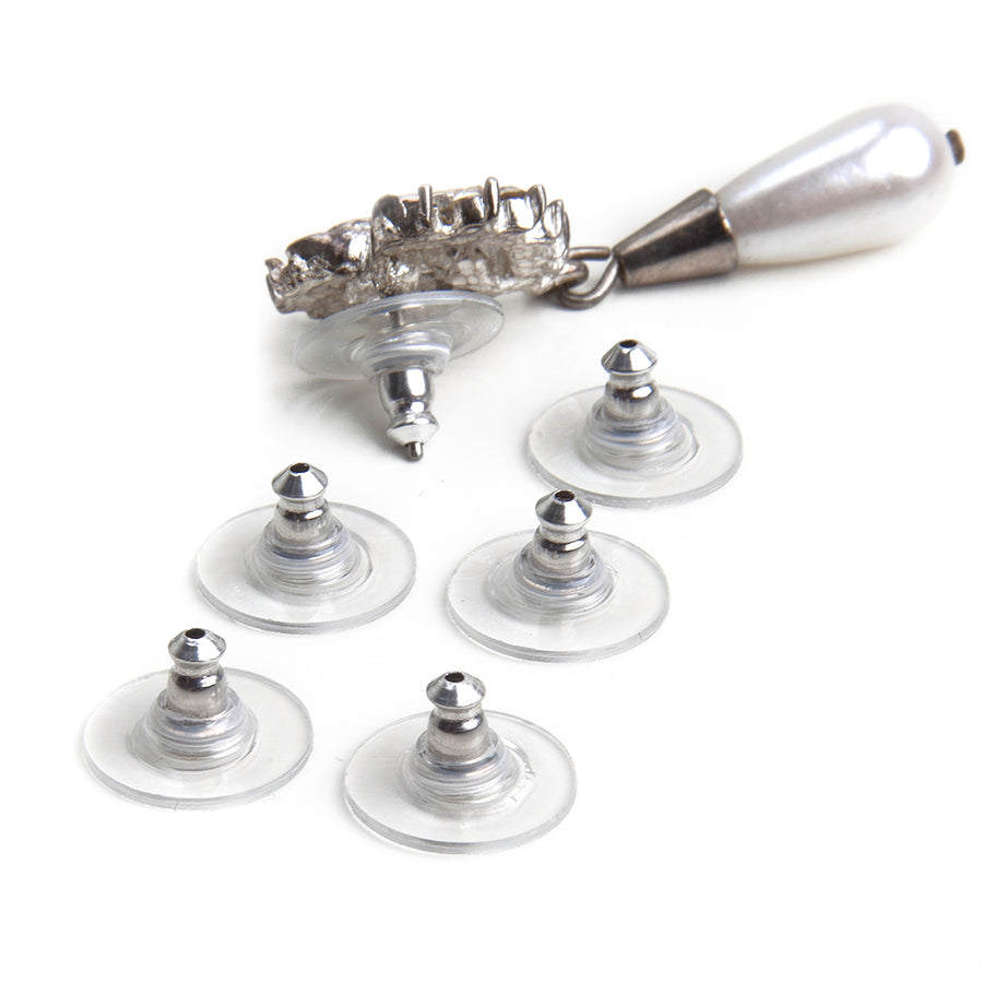 Silvertone and clear disc earring backs laid out next to a silver and pearl dangle post earring showing how the disc earring backs fit into a post earring.