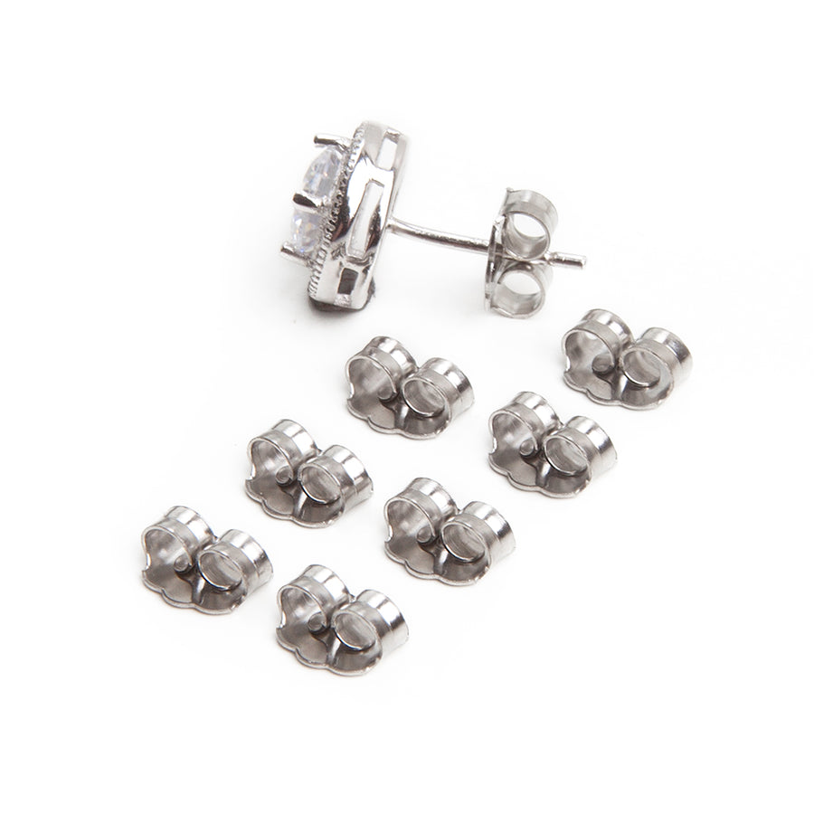 eight butterfly friction earring backs made of stainless steel laid out in two rows of four for a total of eight with an earring in silvertone with large clear diamond in a halo setting against a white background 