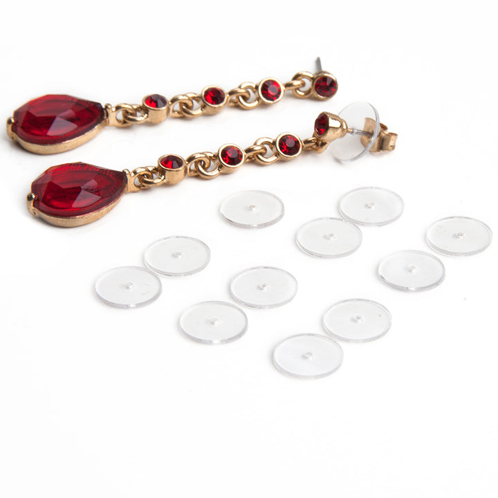 Twelve clear discs with holes in the middle next to a pair of red gemstone dangle post earrings showing how the clear discs fit onto a post earring to provide support.