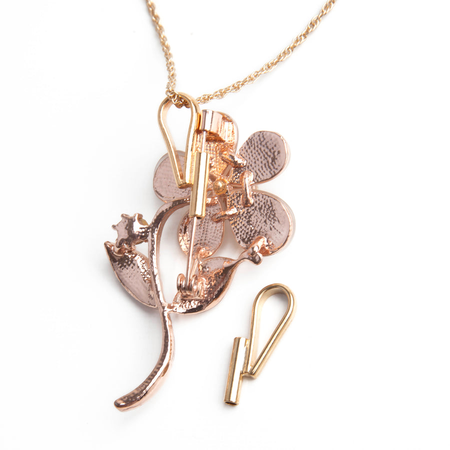 one gold vertical pin to pendant converter laid next to a gold necklace using a gold vertical pin to pendant converter with a gold flower brooch.