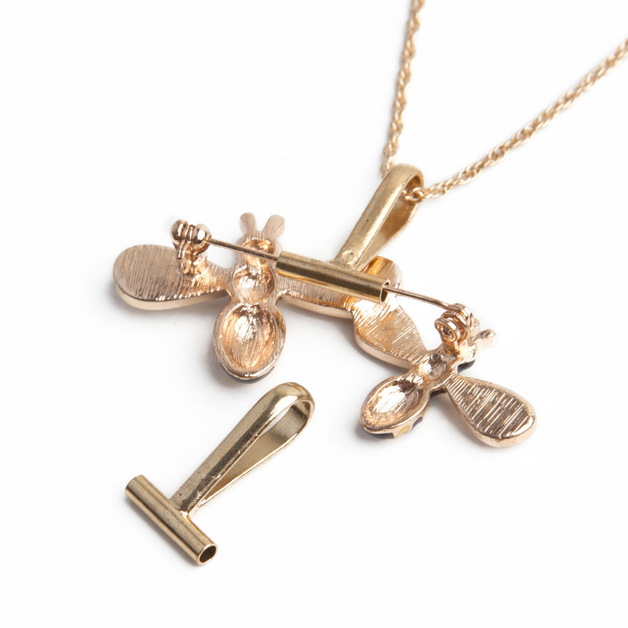 One gold horizontal pin to pendant converters sitting in front of a necklace using a gold horizontal pin to pendant converter with a bumblebee brooch.