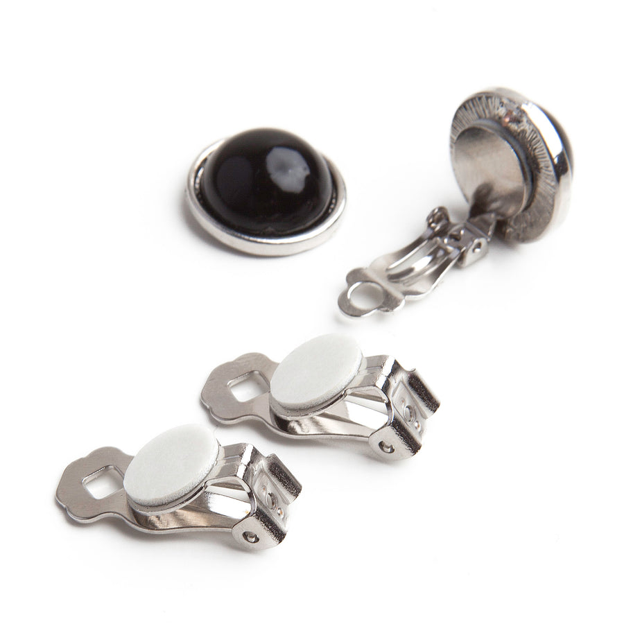 two adhesive clip on earring backings next to a button with a newly added clip on earring back and a remaining unconverted post earring back for reference of before and after