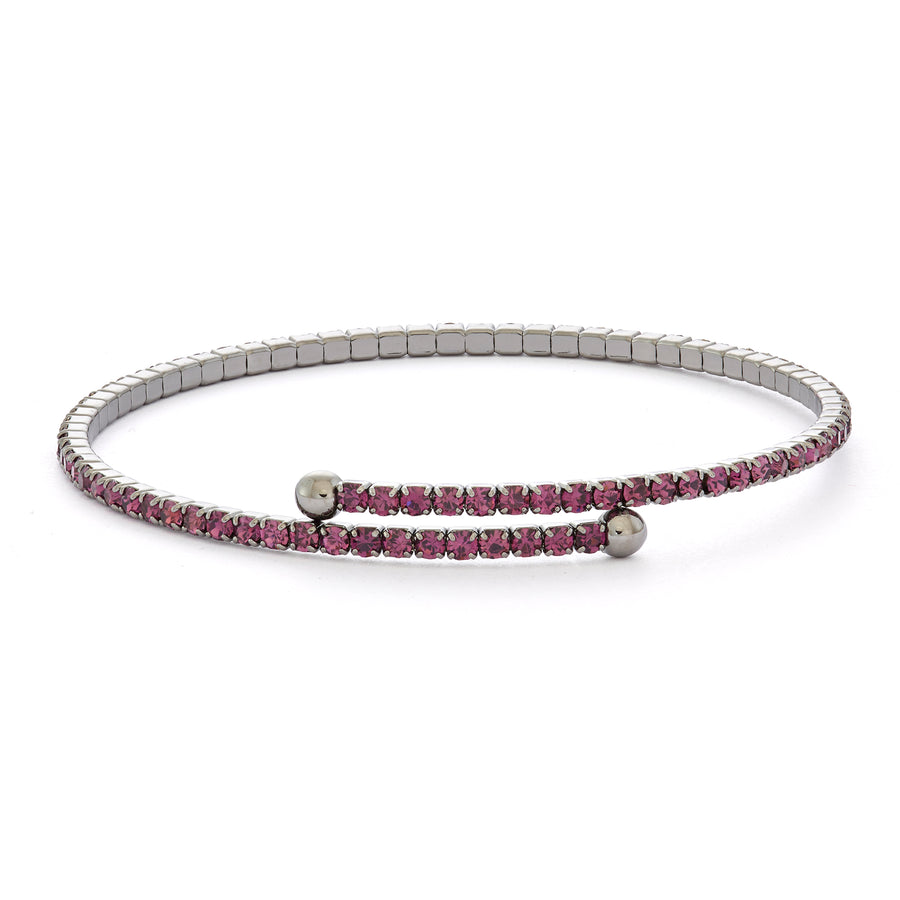 a flexible bangle bracelets with amethyst austrian crystal gemstones and black rhodium plated setting leaning against a white background